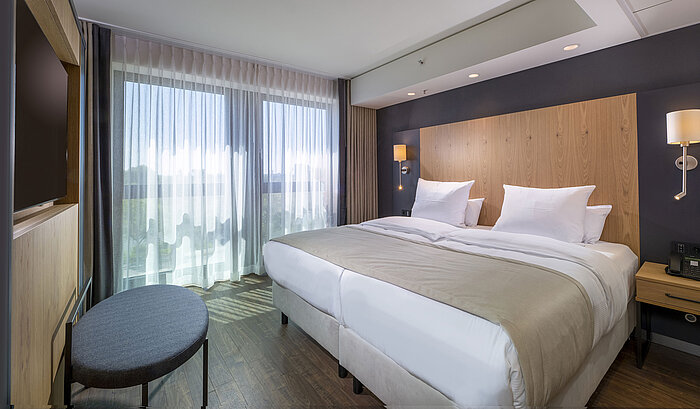 Großzügiges Doppelzimmer mit modernem Design, bequemen Betten und Blick auf die Stadt im Maritim Hotel Ingolstadt.