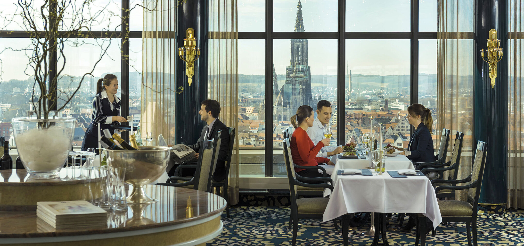 Gäste genießen das Essen mit Blick auf das Ulmer Münster im Panorama-Restaurant des Maritim Hotel Ulm