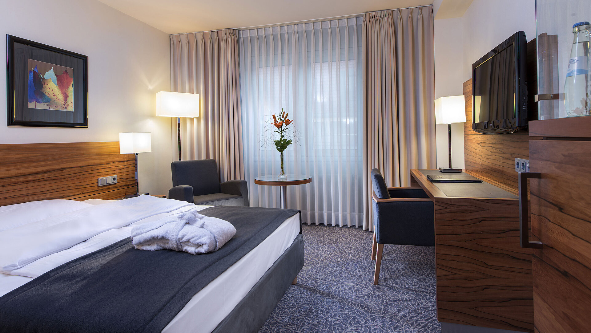 Modernes Doppelzimmer im Maritim Hotel München. Komfortabel ausgestattet mit großem Bett, Arbeitsplatz und Lesesessel.