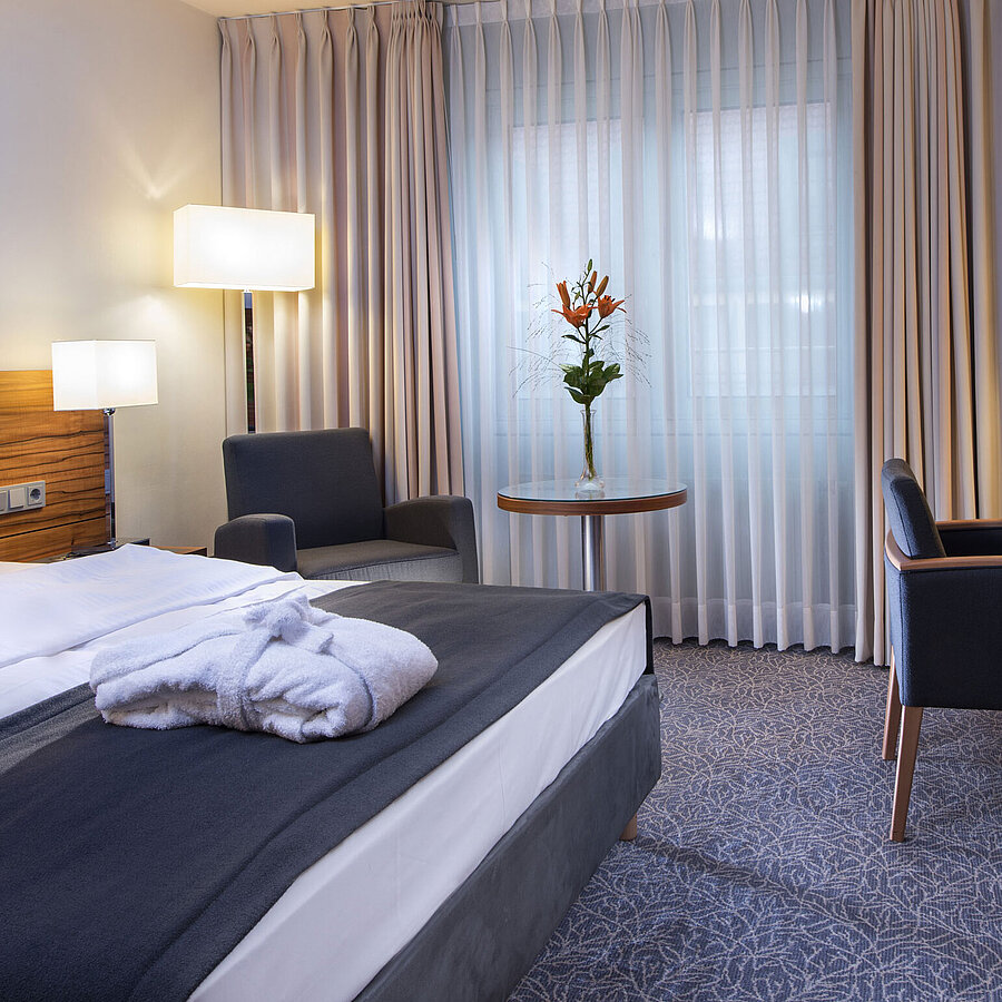 Modernes Doppelzimmer im Maritim Hotel München. Komfortabel ausgestattet mit großem Bett, Arbeitsplatz und Lesesessel.