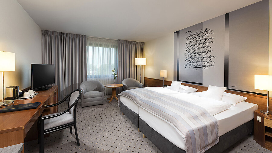 Modernes Classic Doppelzimmer mit gemütlichem Doppelbett, Sitzbereich und Schreibtisch im Maritim Hotel Hannover.