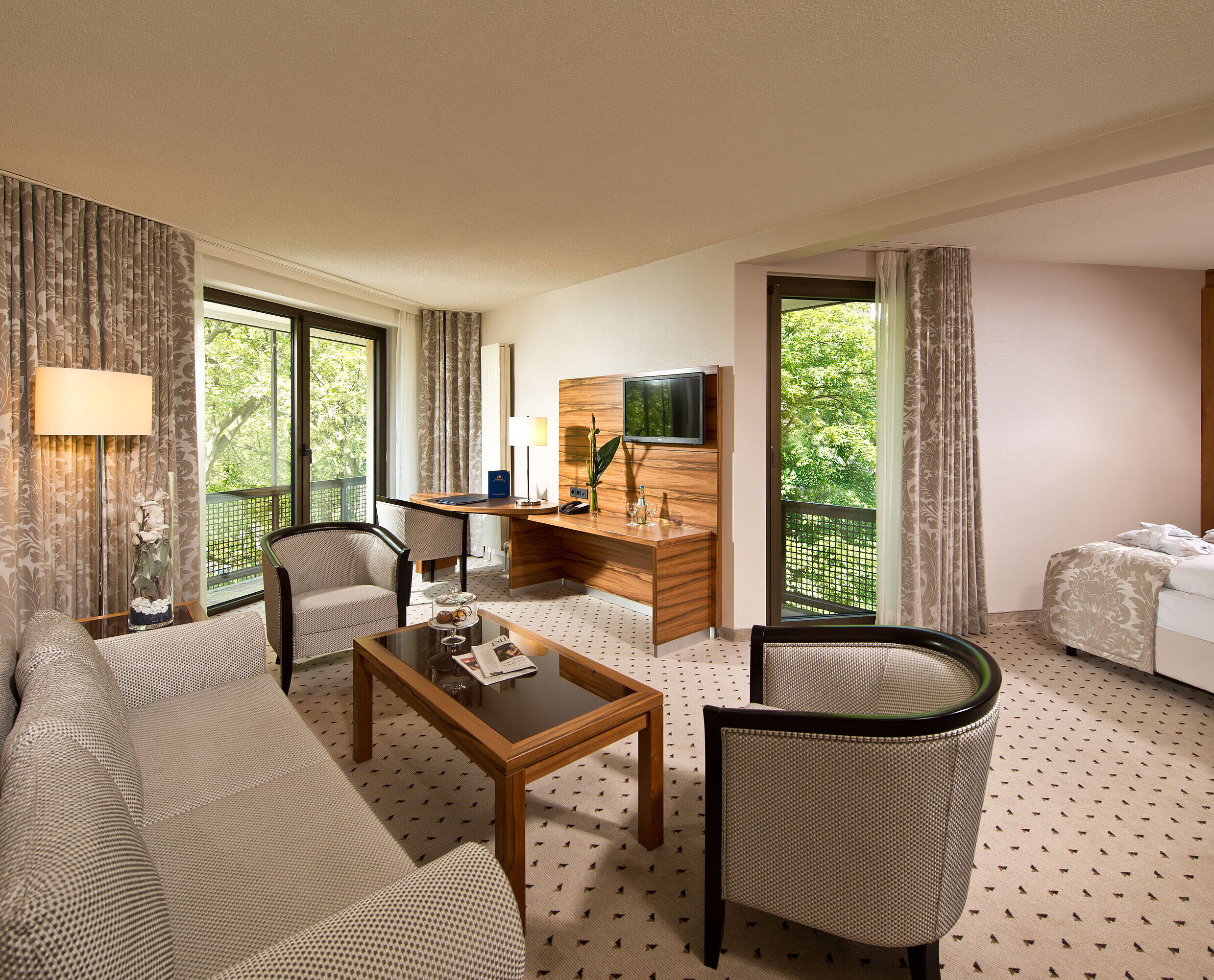 Geräumige Suite im Maritim Hotel Bad Homburg mit separatem Wohnbereich, Balkon und grünem Ausblick.