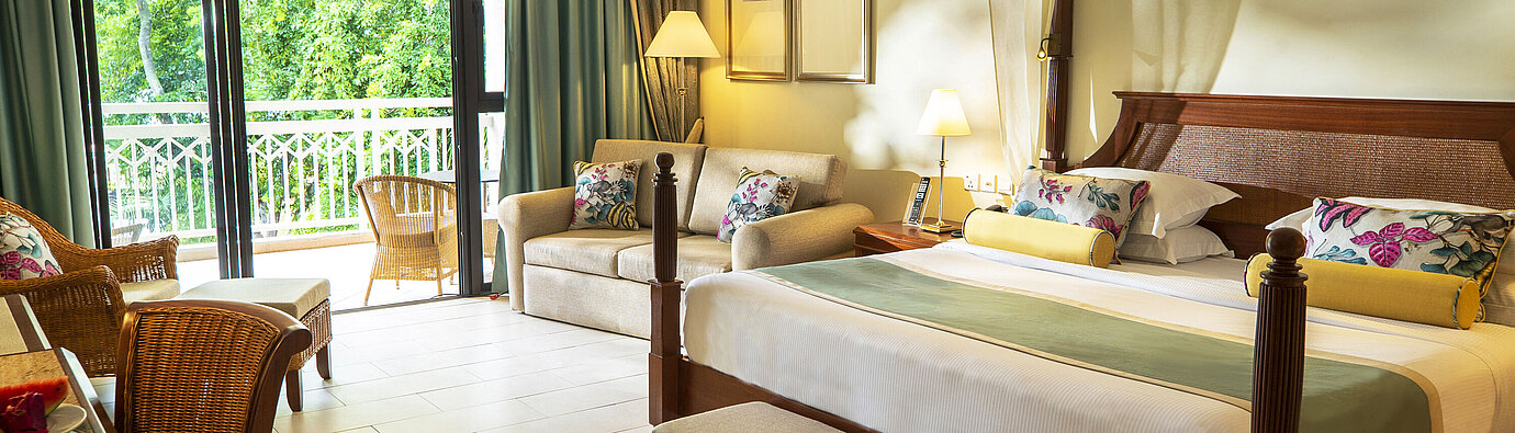 Großzügiges Hotelzimmer mit Himmelbett, Sofa, Balkon und Blick ins Grüne