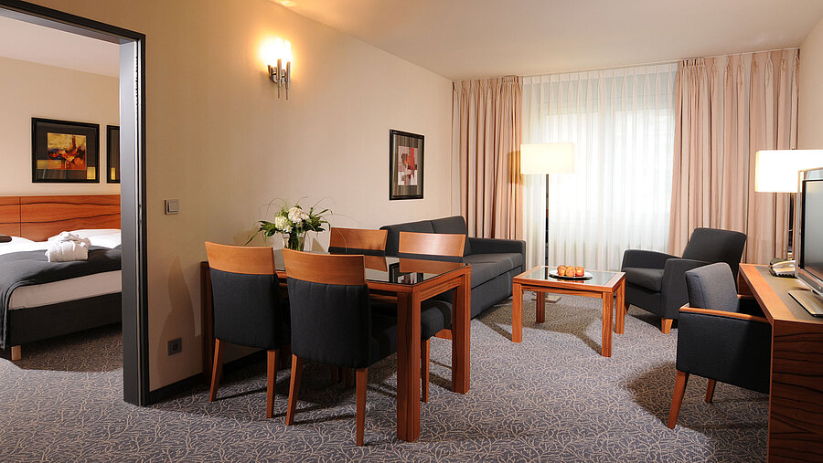 Großzügige Suite mit Wohnzimmer, Esstisch und separatem Schlafzimmer im Maritim Hotel München