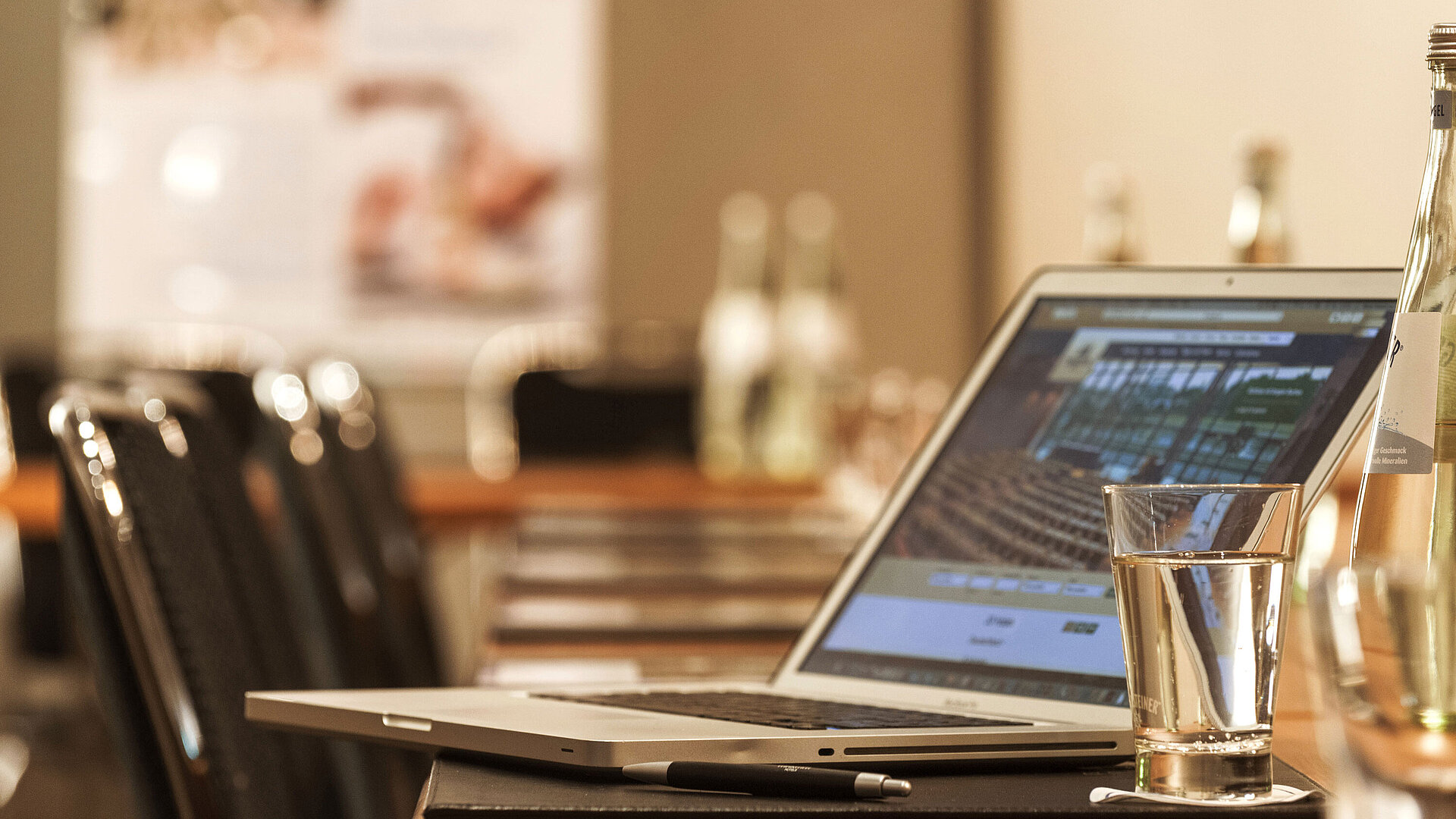 Laptop, Stift und Wasserglas auf Tisch im Konferenzraum des Maritim Hotel München