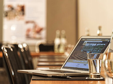 Detailansicht Tagungsraum Laptop, Stift und Wasserglas auf Tisch im Konferenzraum des Maritim Hotel München