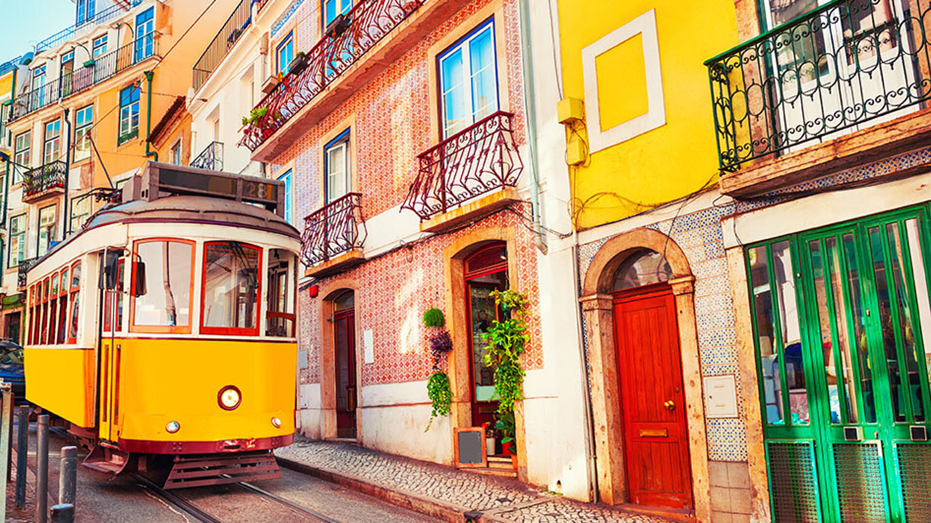 © Alliance - AdobeStock.com Gelbe Tram fährt durch die bunten Altstadtstraßen von Lissabon