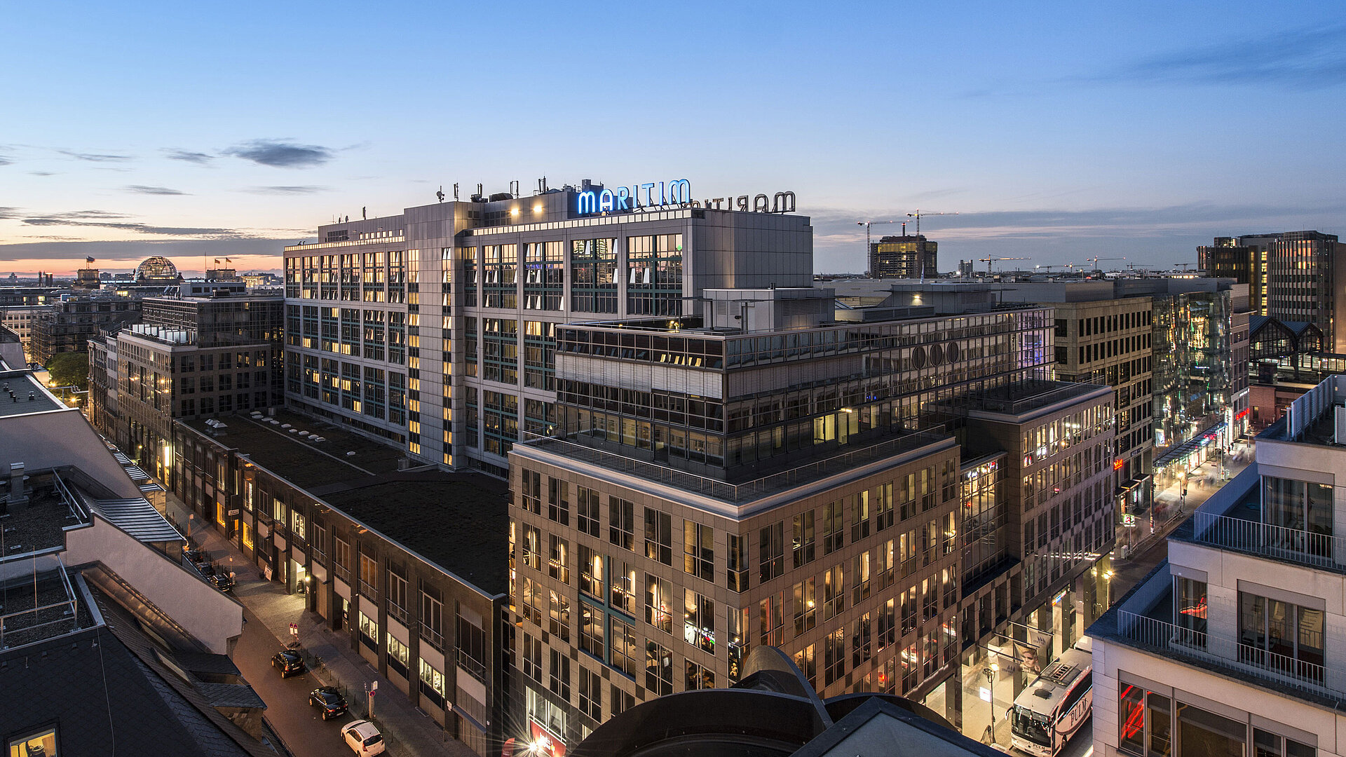 Blick auf das Maritim proArte Hotel Berlin bei Dämmerung, umgeben von modernen Gebäuden im Herzen Berlins.