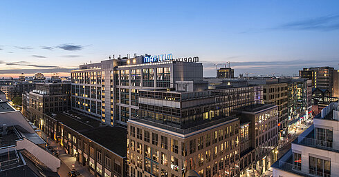 Blick auf das Maritim proArte Hotel Berlin bei Dämmerung, umgeben von modernen Gebäuden im Herzen Berlins.