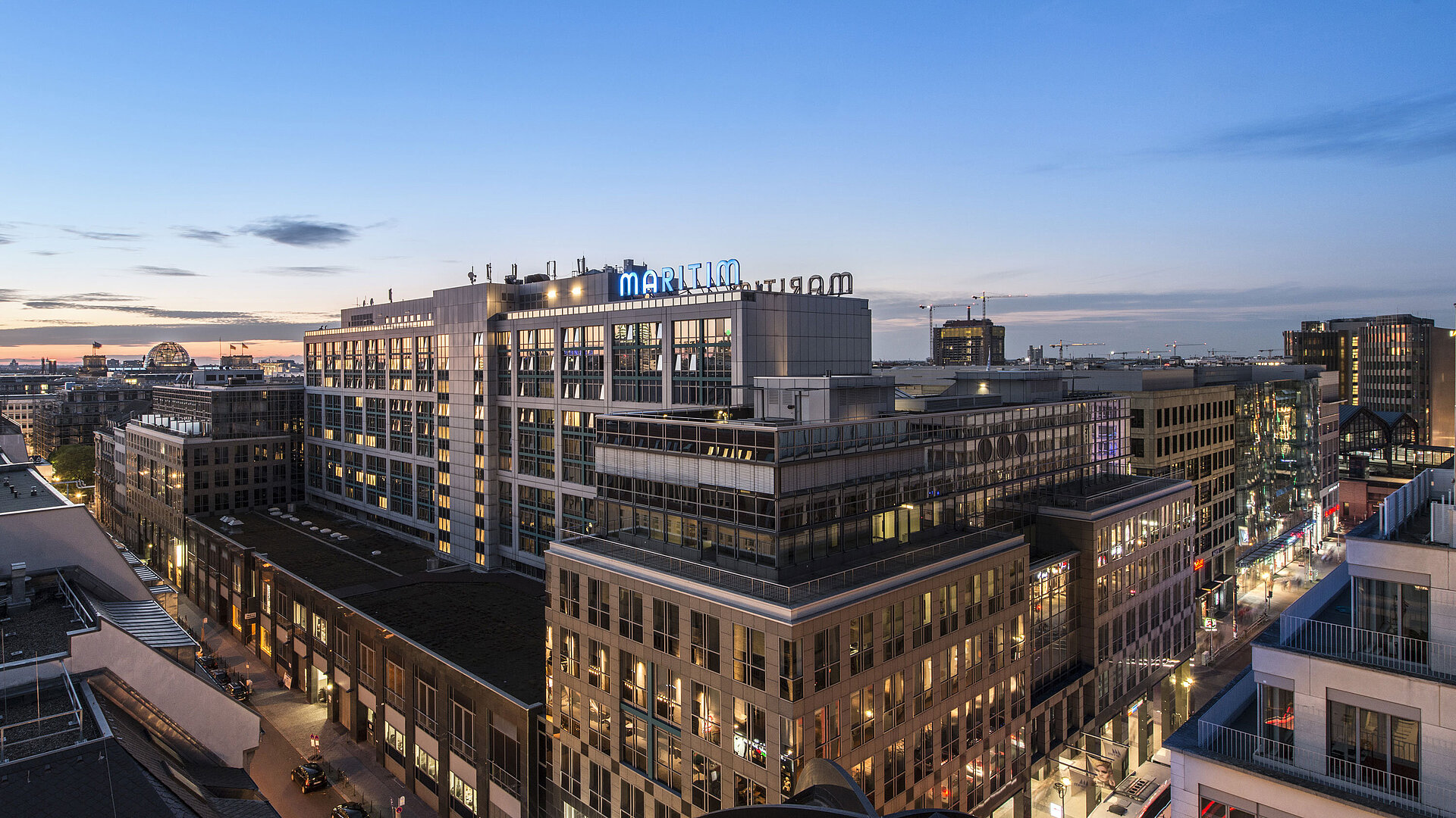 Blick auf das Maritim proArte Hotel Berlin bei Dämmerung, umgeben von modernen Gebäuden im Herzen Berlins.