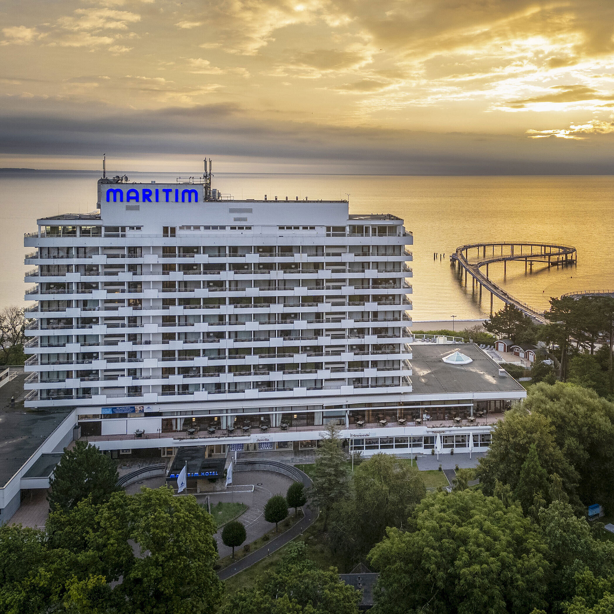 Außenansicht Maritim Seehotel Timmendorfer Strand bei Sonnenaufgang mit Seebrücke und Meerblick.