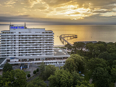 Maritim Seehotel Timmendorfer Strand bei Sonnenaufgang mit Seebrücke und Meerblick.