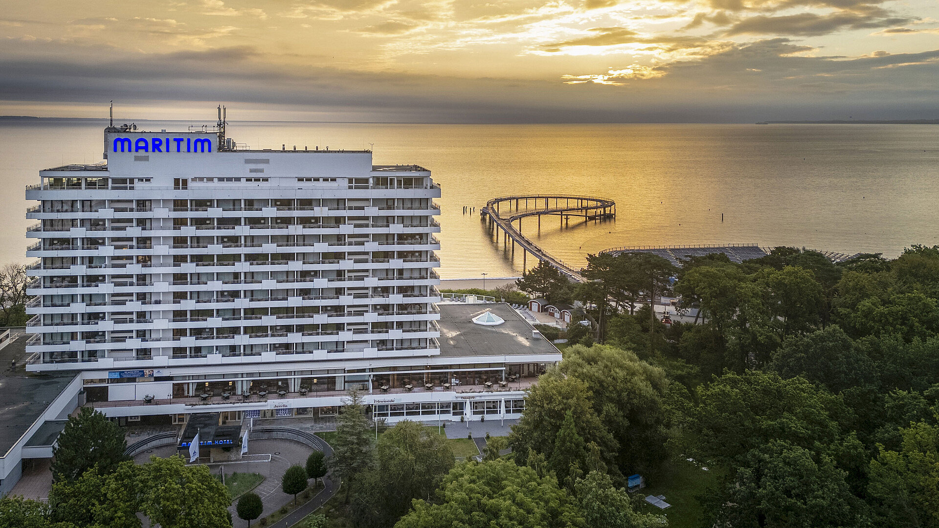 Maritim Seehotel Timmendorfer Strand bei Sonnenaufgang mit Seebrücke und Meerblick.
