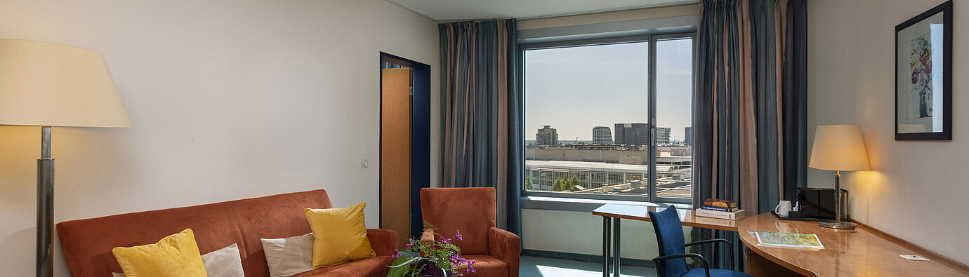 Junior Suite im Maritim Hotel Frankfurt mit separatem Wohnbereich, Sofa, Schreibtisch und Panoramablick auf die Stadt.