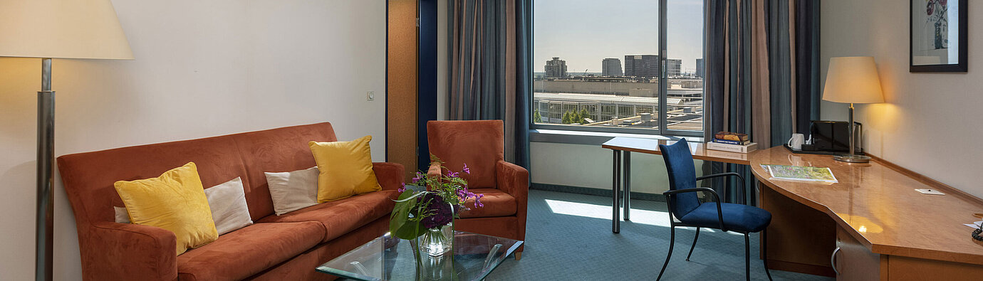Junior Suite im Maritim Hotel Frankfurt mit separatem Wohnbereich, Sofa, Schreibtisch und Panoramablick auf die Stadt.