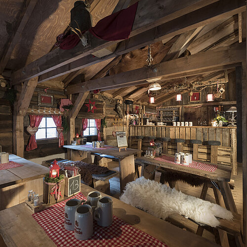 Almhütte Rustikale Bar und festlich gedeckte Holztische mit roten Vorhängen in der ElbAlm