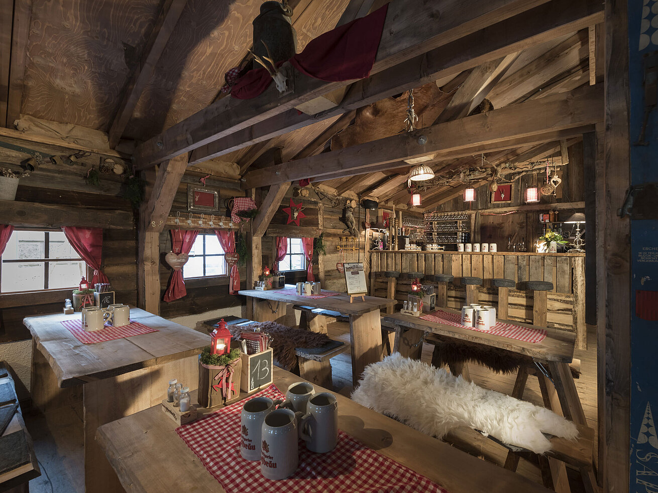 Almhütte Rustikale Bar und festlich gedeckte Holztische mit roten Vorhängen in der Maritim Alm Stuttgart