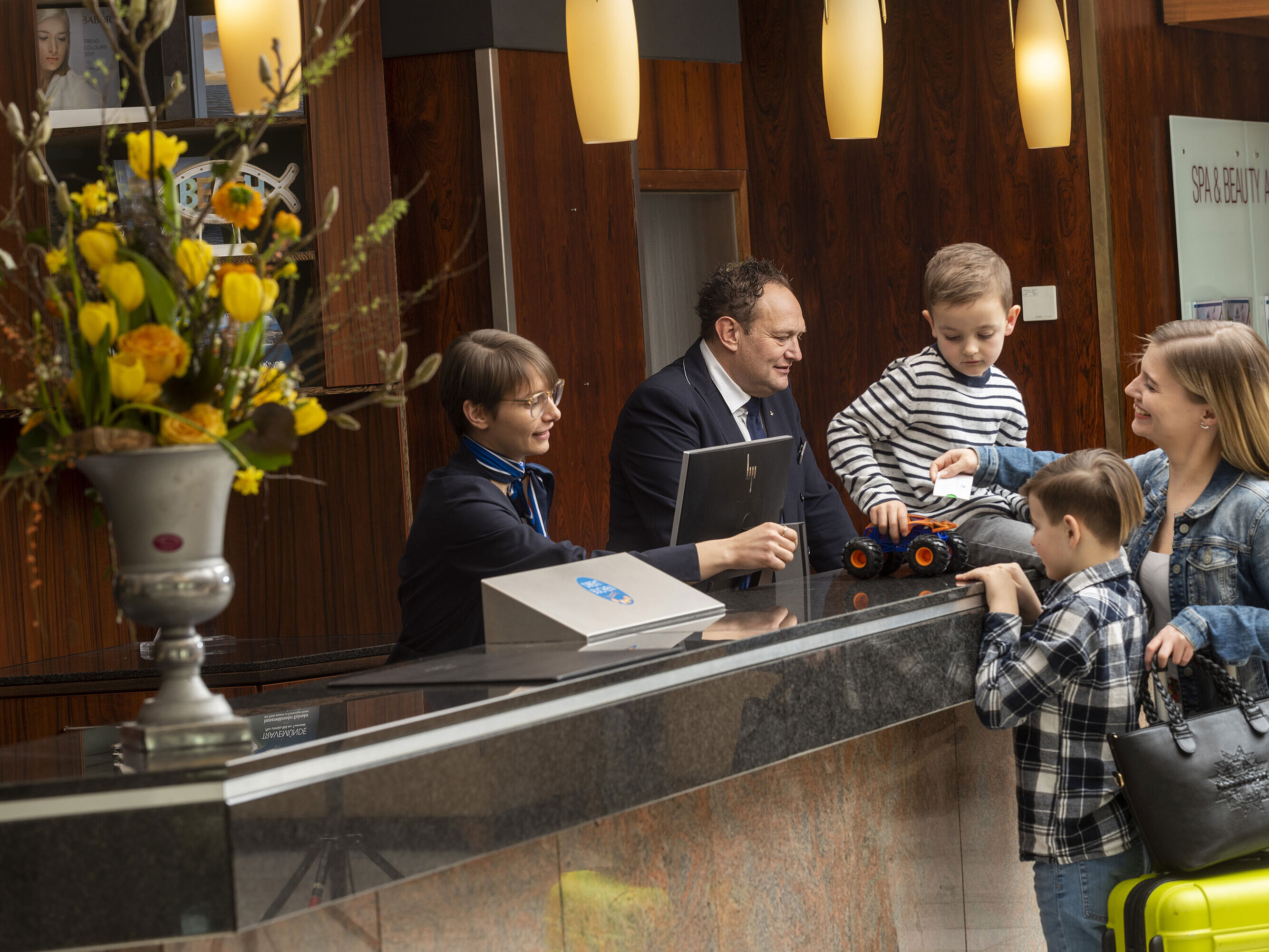 Rezeptionsteam begrüßt eine Familie mit Kindern freundlich im Maritim Hotel Travemünde