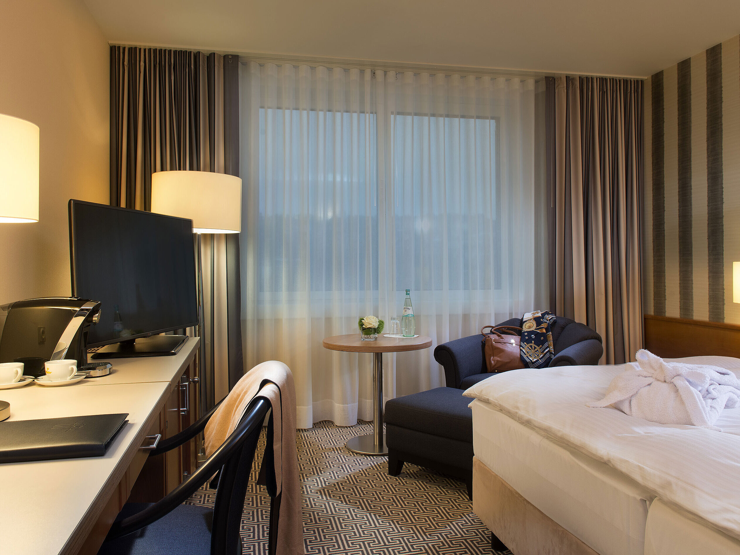 Doppelzimmer mit Sessel, Schreibtisch, Kaffeemaschine und Tageslicht im Maritim Hotel Stuttgart