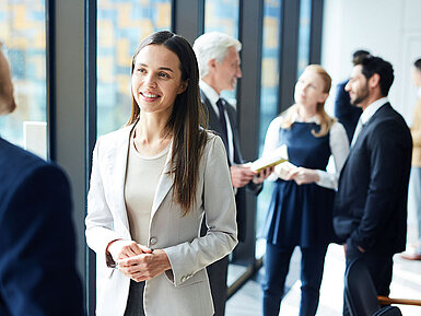 © pressmaster – AdobeStock.com Business-Netzwerken während Konferenzpause im modernen Tagungsbereich