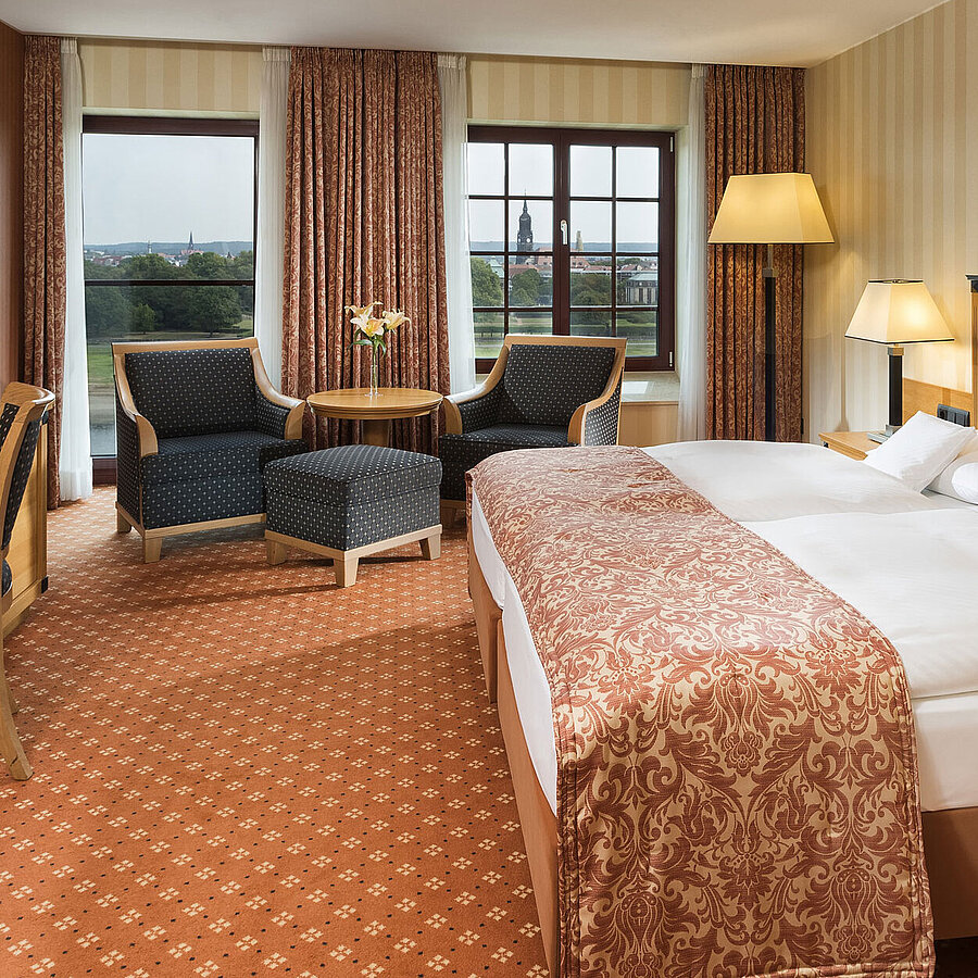 Superior Zimmer im Maritim Hotel Dresden mit elegantem Doppelbett, Schreibtisch und Sitzbereich sowie Blick auf die Stadt.
