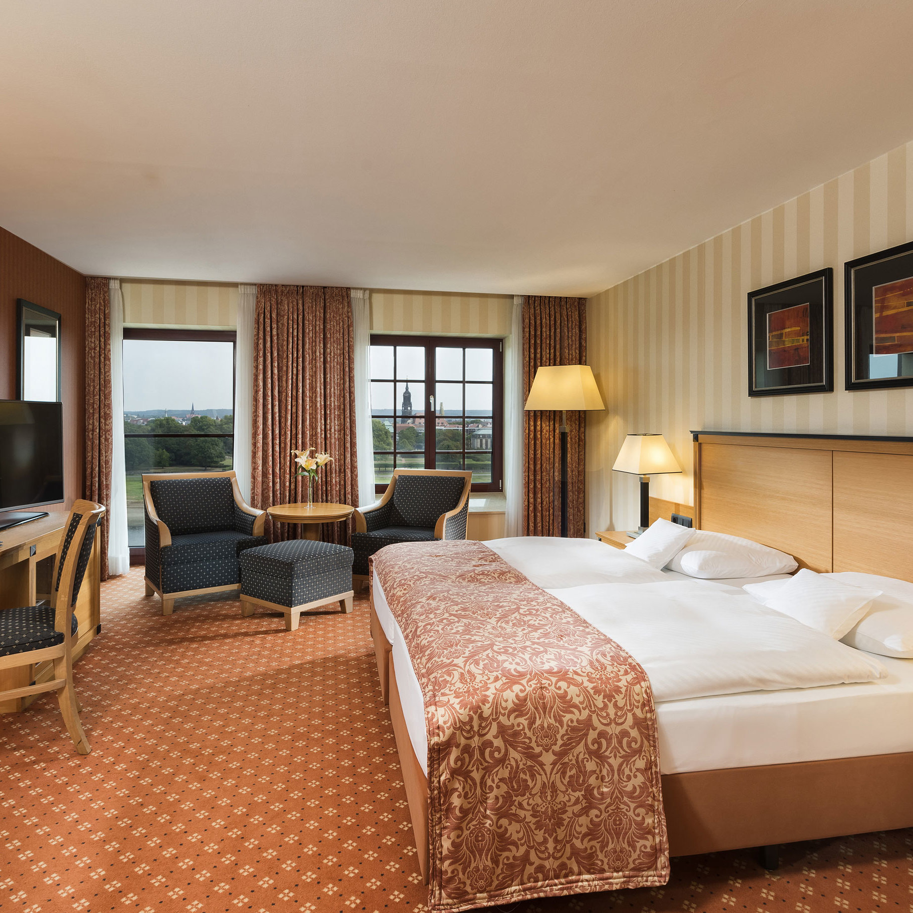 Superior Zimmer Superior Zimmer im Maritim Hotel Dresden mit elegantem Doppelbett, Schreibtisch und Sitzbereich sowie Blick auf die Stadt.