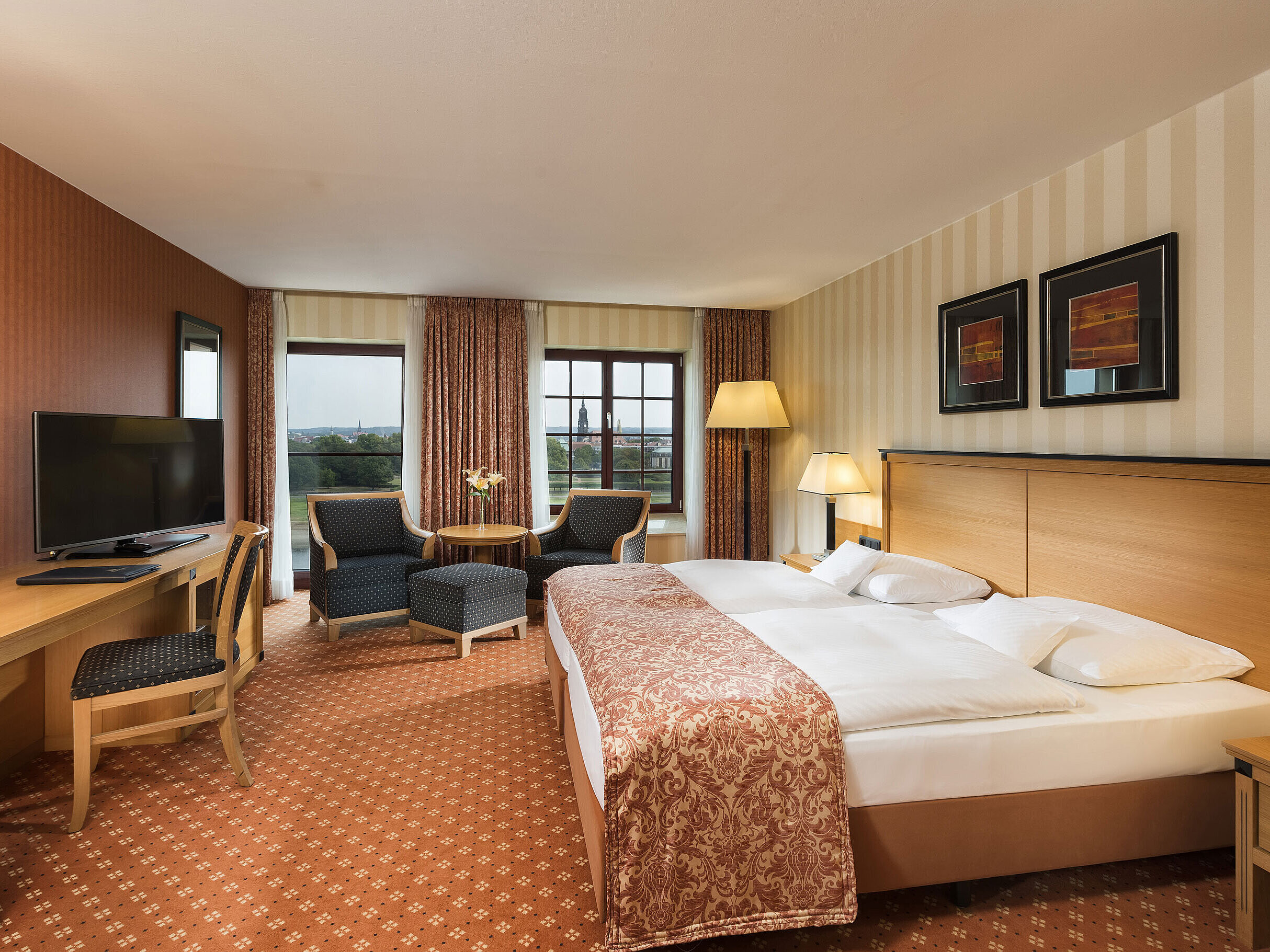 Superior Zimmer im Maritim Hotel Dresden mit elegantem Doppelbett, Schreibtisch und Sitzbereich sowie Blick auf die Stadt.