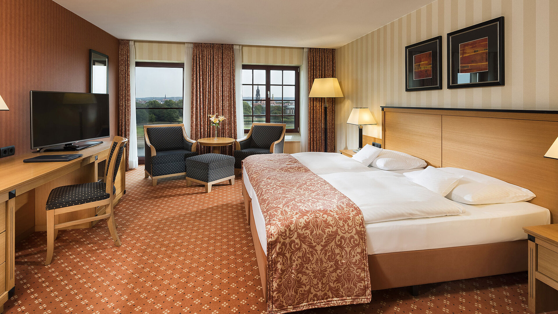 Superior Zimmer im Maritim Hotel Dresden mit elegantem Doppelbett, Schreibtisch und Sitzbereich sowie Blick auf die Stadt.