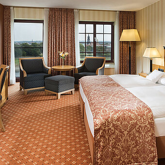 Superior Zimmer im Maritim Hotel Dresden mit elegantem Doppelbett, Schreibtisch und Sitzbereich sowie Blick auf die Stadt.