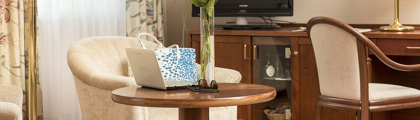 Gemütlicher Sitzbereich mit Rosen, Laptop und TV im Zimmer des Maritim Hotel Bad Wildungen