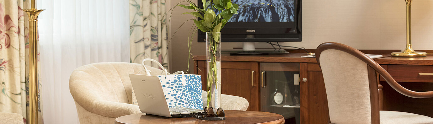 Gemütlicher Sitzbereich mit Rosen, Laptop und TV im Zimmer des Maritim Hotel Bad Wildungen