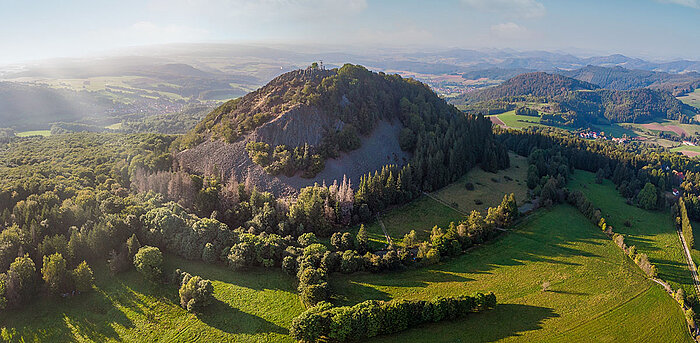 Luftaufnahme der Milseburg bei Hilders mit grünen Wiesen und bewaldeten Hängen