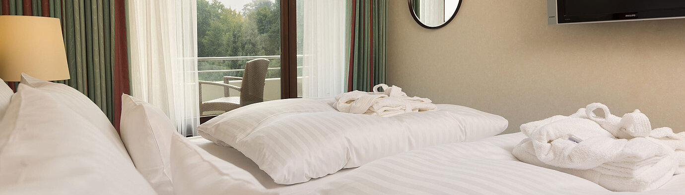 Junior Suite  Doppelbett mit TV, Bademantel und Ausblick auf den Balkon im Maritim Hotel Bad Salzuflen