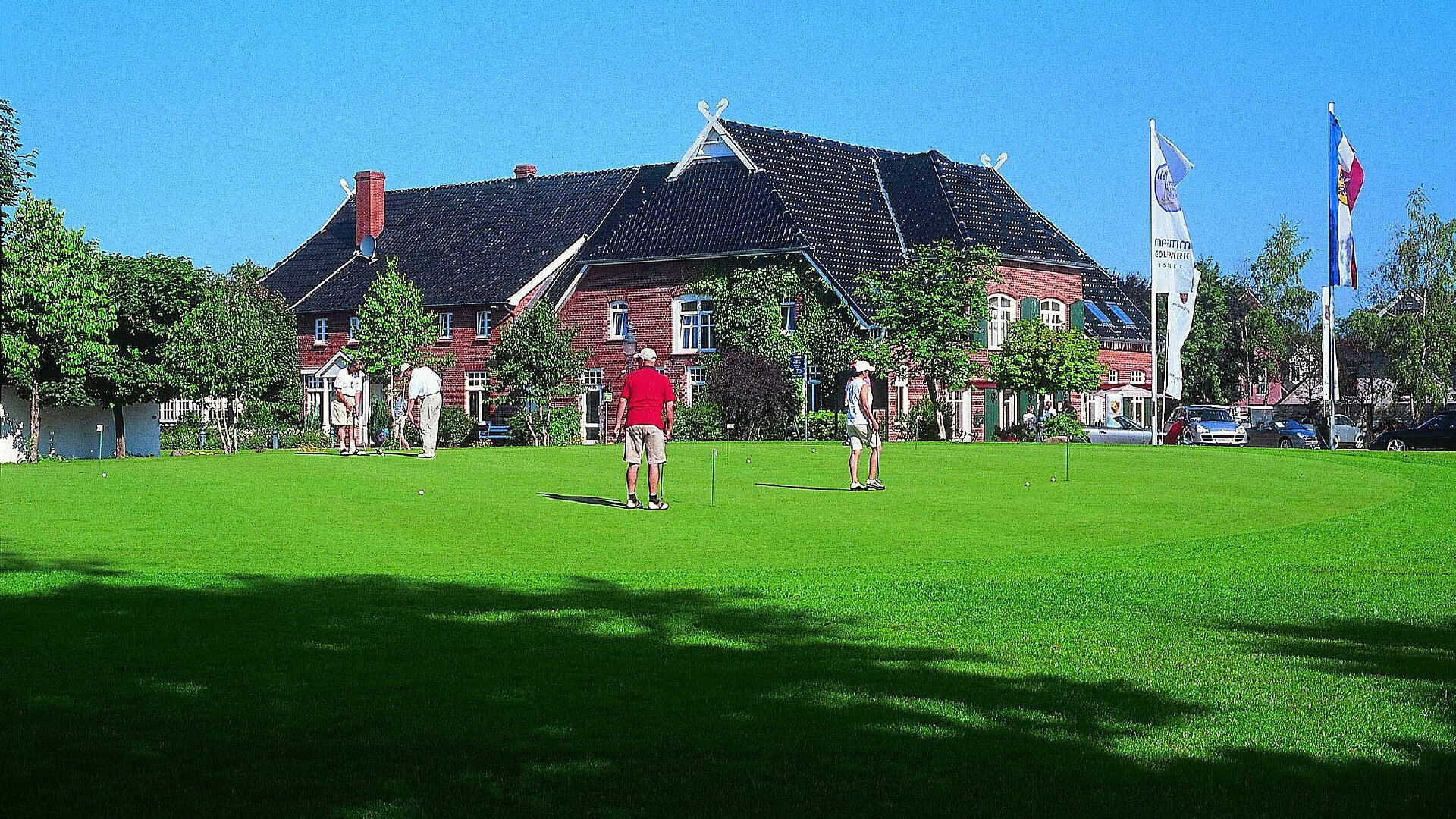 Golfspieler vor dem Clubhaus Spieler auf dem Rasen des Maritim Golfparks vor dem Clubhaus bei sonnigem Wetter