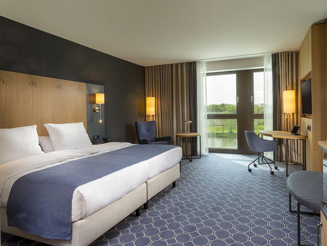 Geräumiges Doppelzimmer im Maritim Hotel Ingolstadt mit Bett, Schreibtisch und Blick auf den Fluss.