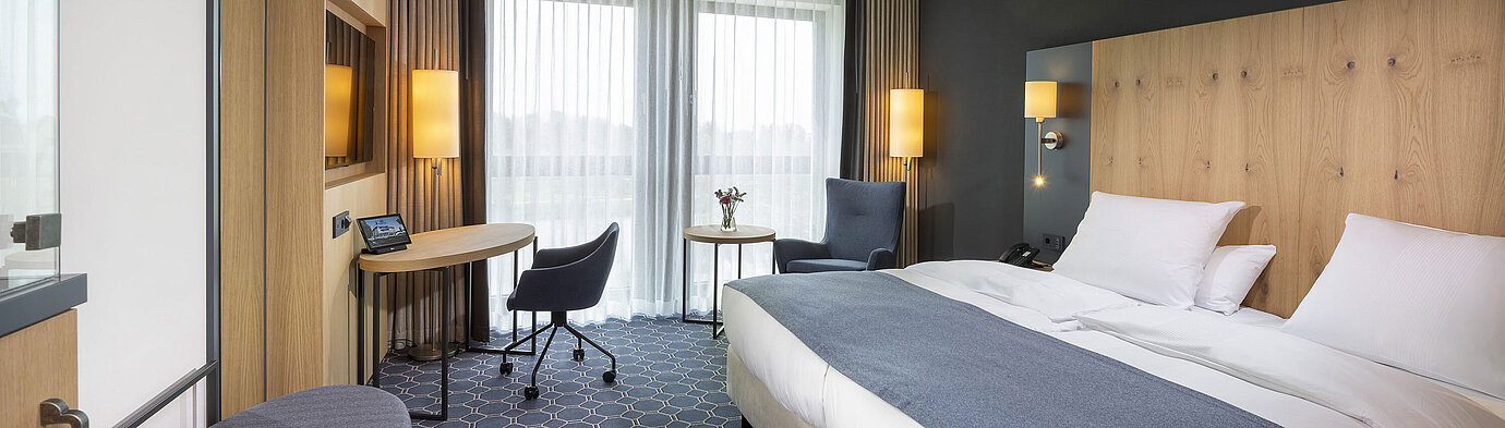 Geräumiges Doppelzimmer im Maritim Hotel Ingolstadt mit Schreibtisch, Sitzbereich und Balkon.