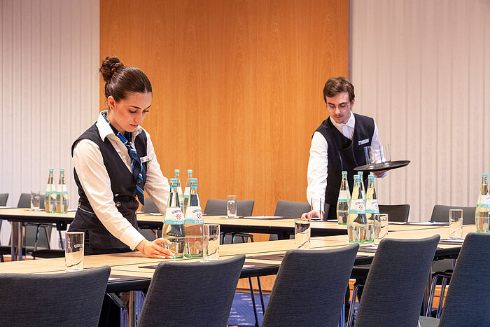 Mitarbeitende bereiten einen Tagungsraum im Maritim Hotel Würzburg für eine Veranstaltung vor