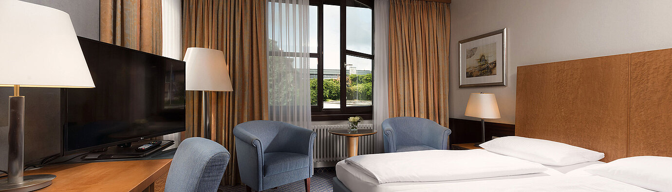 Classic Zimmer im Maritim Hotel Fulda mit gemütlichem Doppelbett, Schreibtisch, Sitzbereich und großem Fenster.