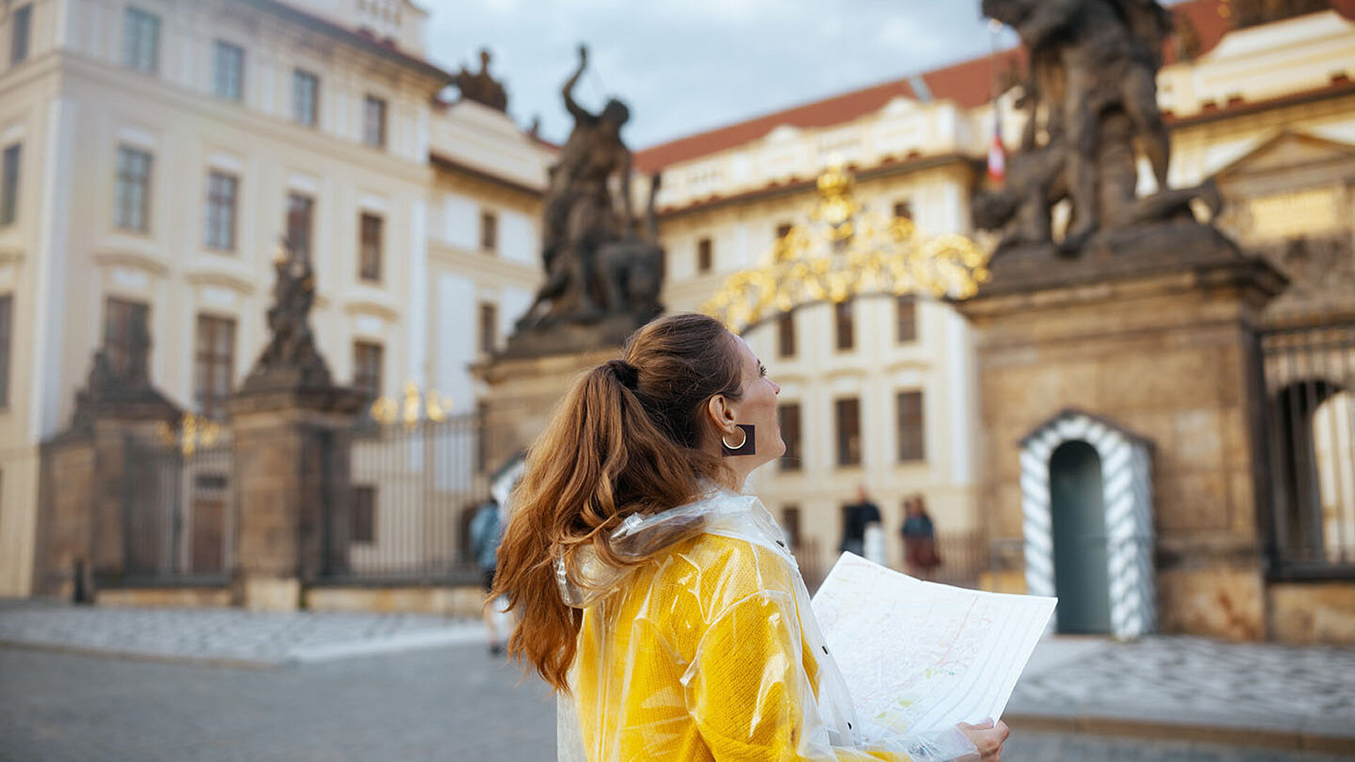 © Alliance - AdobeStock.com Touristin mit Karte vor dem Eingang der Prager Burg