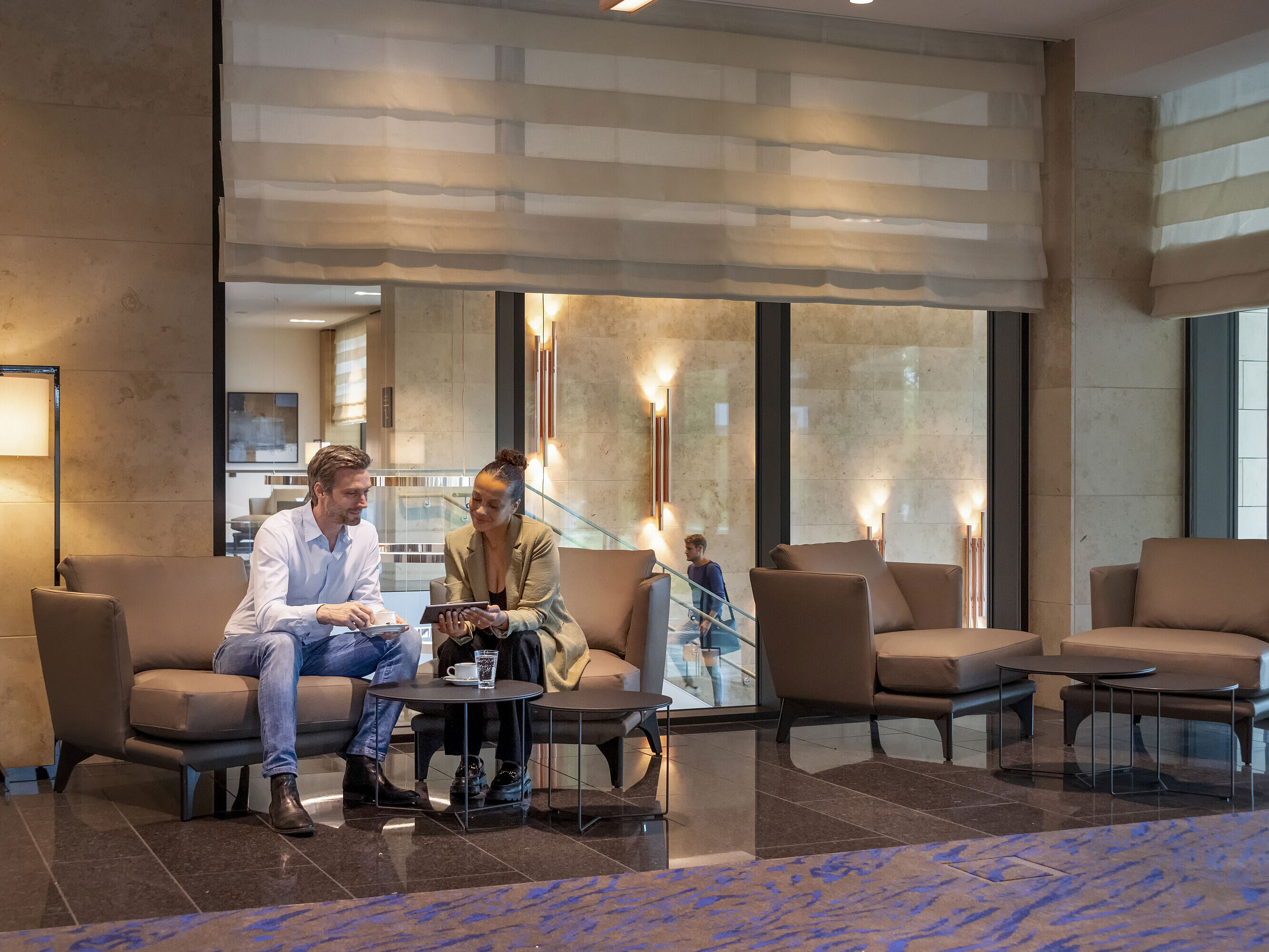 Mann und Frau sitzen in der Lobby des Maritim Hotel Ingolstadt und unterhalten sich bei Kaffee.