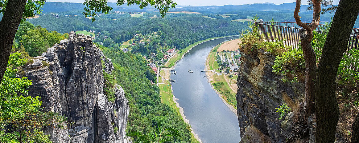 Aussicht von Felsen auf die Elbe in der Sächsischen Schweiz mit grünem Tal und Dorf im Sommer