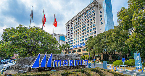 Außenansicht Außenansicht des Maritim Hotels mit großem Logo, gepflegten Grünanlagen und Flaggen vor dem Hoteleingang