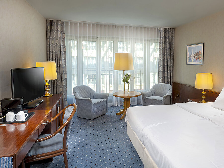Classic Zimmer im Maritim Hotel Köln mit Doppelbett, gemütlicher Sitzgelegenheit, Schreibtisch und TV.