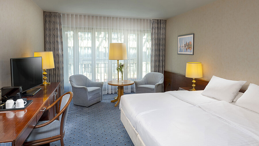 Classic Zimmer im Maritim Hotel Köln mit Doppelbett, gemütlicher Sitzgelegenheit, Schreibtisch und TV.