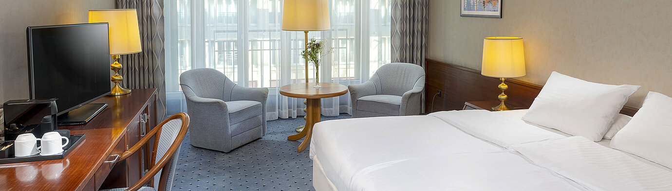 Classic Zimmer im Maritim Hotel Köln mit Doppelbett, gemütlicher Sitzgelegenheit, Schreibtisch und TV.