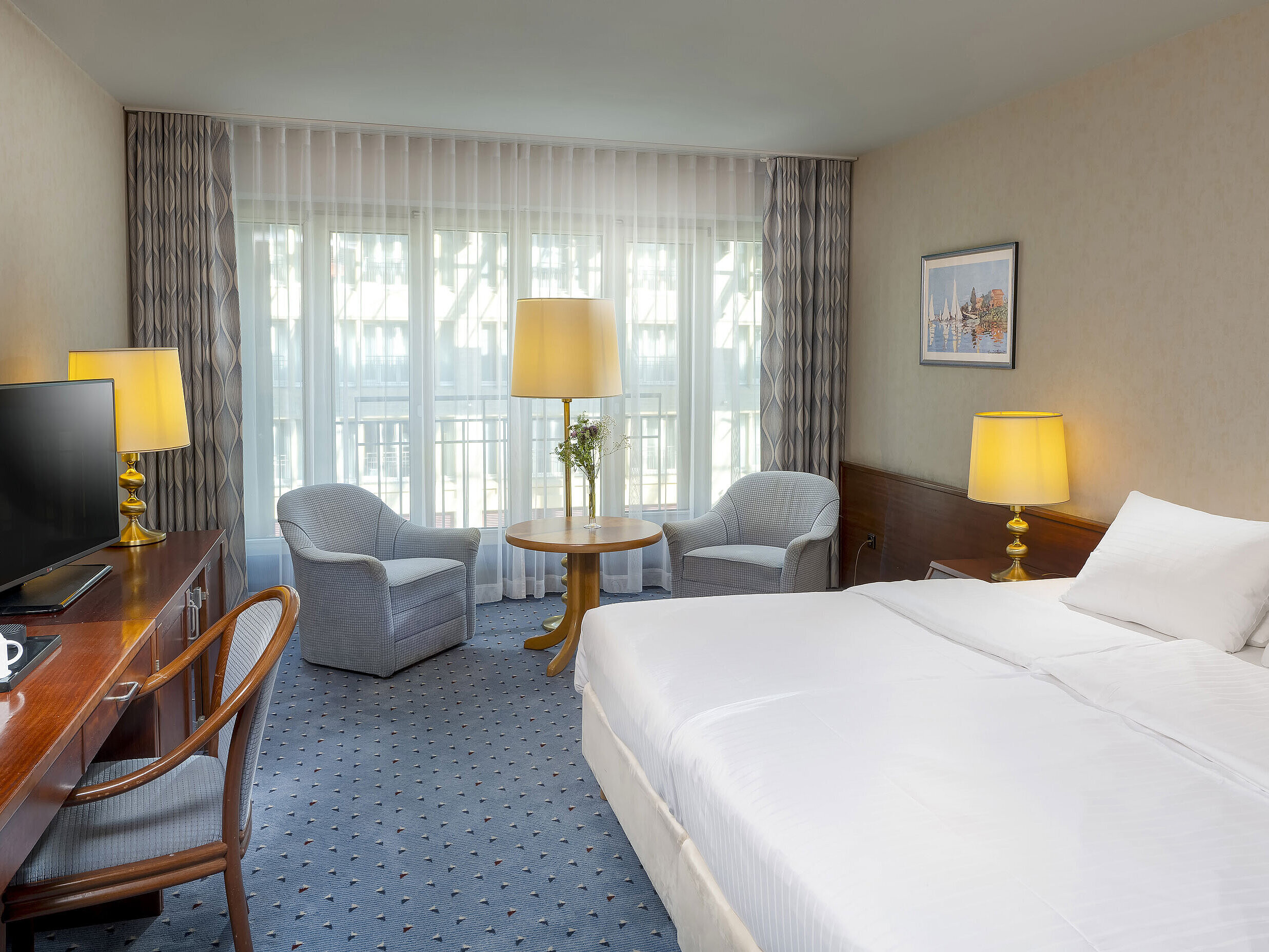 Classic Zimmer im Maritim Hotel Köln mit Doppelbett, gemütlicher Sitzgelegenheit, Schreibtisch und TV.