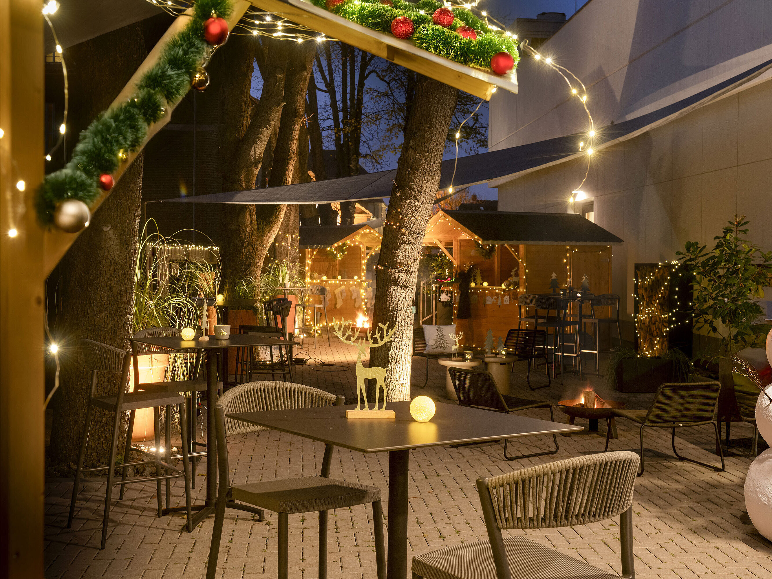 Festlich geschmückter Weihnachtsmarkt im Maritim Hotel Darmstadt mit Lichterketten, dekorierten Hütten und einem Schneemann.
