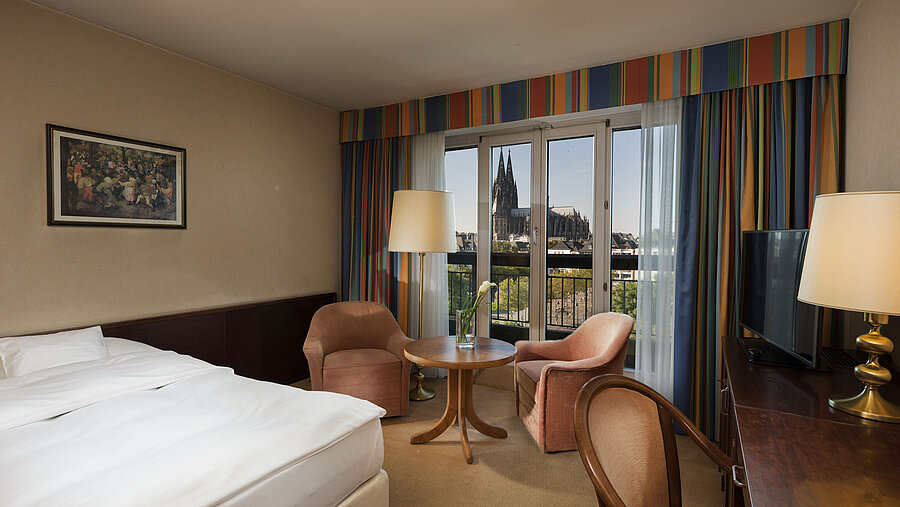 Superior-Zimmer im Maritim Hotel Köln mit Sitzbereich, komfortablem Bett und Blick auf den Kölner Dom.