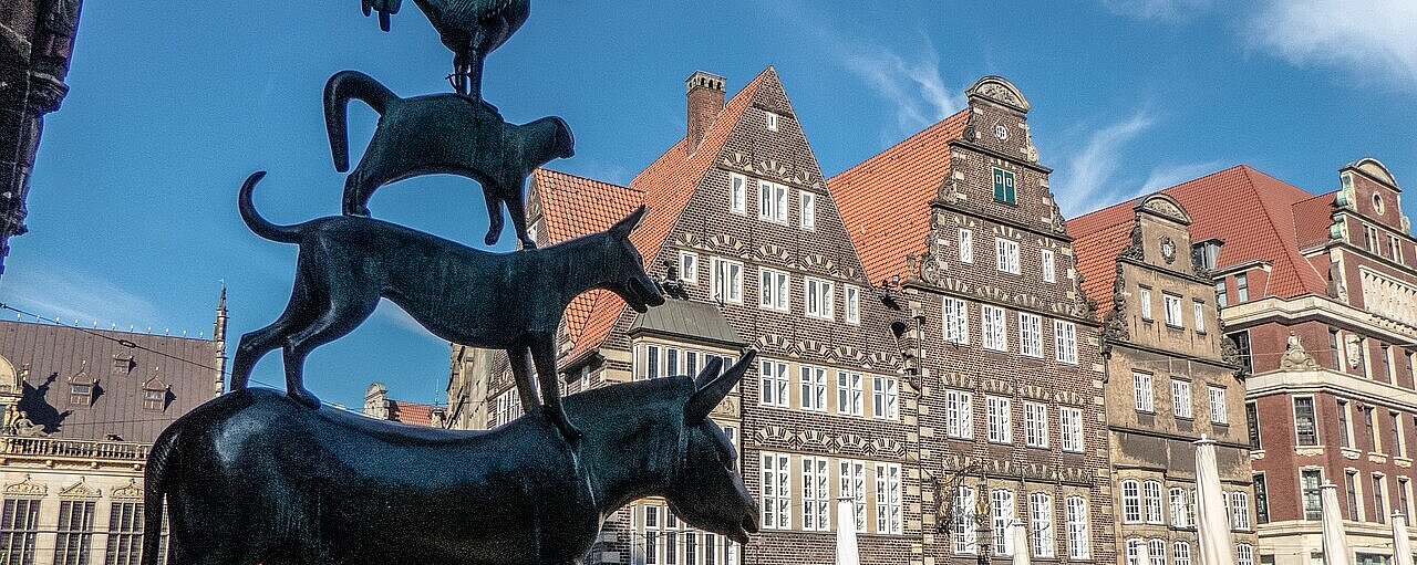 Bronzeskulptur der Bremer Stadtmusikanten auf dem Marktplatz in Bremen vor historischen Gebäuden der Altstadt.