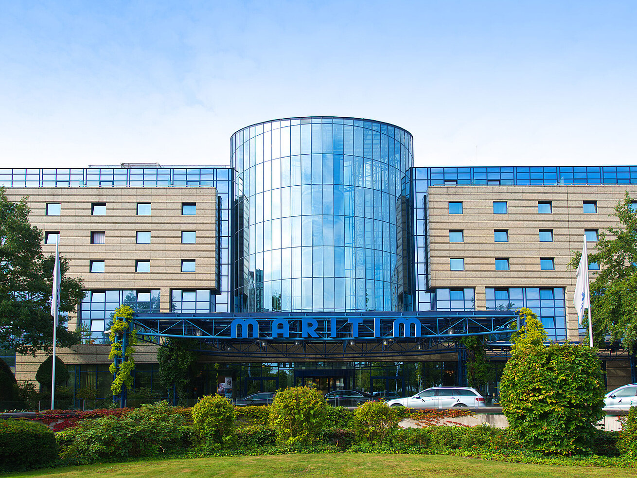 Außenansicht des Maritim Hotels Bonn mit moderner Glasfassade und gepflegter Gartenanlage im Vordergrund.